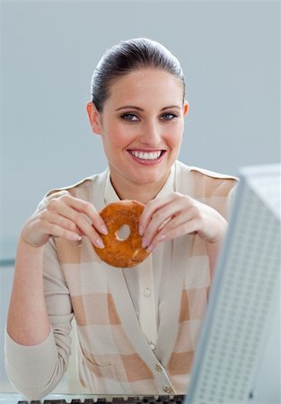 Young businesswoman eating a donut at her desk Stock Photo - Budget Royalty-Free & Subscription, Code: 400-05224386