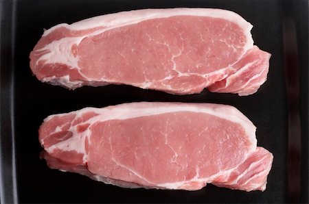 Two raw pork steaks on the black square plate macro shot Stock Photo - Budget Royalty-Free & Subscription, Code: 400-05224669