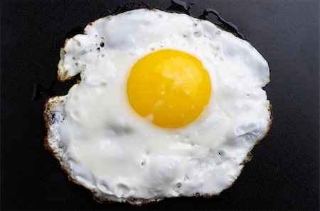 Fried egg over black textured plate background Fotografie stock - Microstock e Abbonamento, Codice: 400-05226389