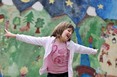 happy young girl posing and jumping with abstract urban style painting bacground begind Stock Photo - Budget Royalty-Free & Subscription, Code: 400-05227175