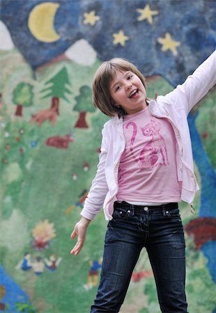 happy young girl posing and jumping with abstract urban style painting bacground begind Stock Photo - Budget Royalty-Free & Subscription, Code: 400-05227172