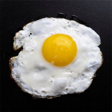 Fried egg over black textured plate background Fotografie stock - Microstock e Abbonamento, Codice: 400-05228238