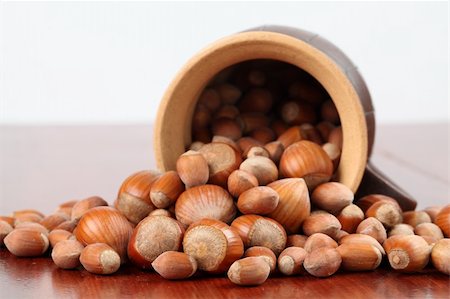 simsearch:400-06520688,k - Ceramic mug with spilled different-sized hazelnuts on a wooden table Stock Photo - Budget Royalty-Free & Subscription, Code: 400-05228290