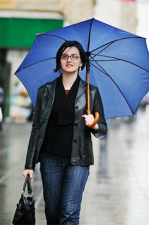 rainfall - one young happy woman walking in cyti with rainy weater and blue umbrella Stock Photo - Budget Royalty-Free & Subscription, Code: 400-05223384