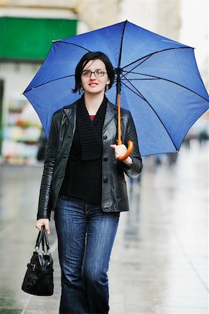rainfall - one young happy woman walking in cyti with rainy weater and blue umbrella Stock Photo - Budget Royalty-Free & Subscription, Code: 400-05223383