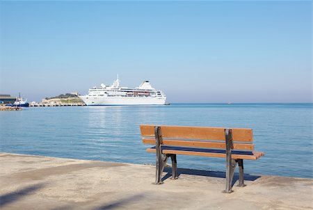 simsearch:400-04042153,k - Small brown ampty bench on the marina with a white holiday cruise liner in the port of Kusadasi, Turkey, on the Aegean. Photographie de stock - Aubaine LD & Abonnement, Code: 400-05223555