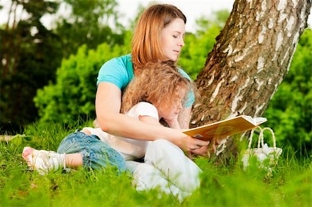 simsearch:400-05248187,k - young mother sitting in grass under tree and reading book to her small daughter who is lying on knees of her mother Photographie de stock - Aubaine LD & Abonnement, Code: 400-05234383