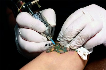 A tattoo artist applying his craft onto the hand of a female Stock Photo - Budget Royalty-Free & Subscription, Code: 400-05230655