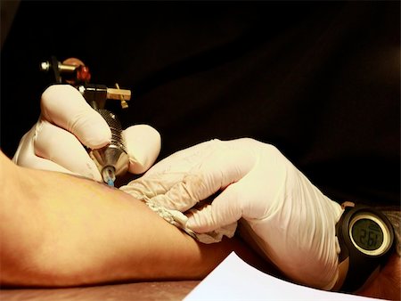 A tattoo artist applying his craft onto the hand of a female Stock Photo - Budget Royalty-Free & Subscription, Code: 400-05230656