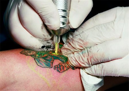 simsearch:400-03921001,k - A tattoo artist applying his craft onto the hand of a female Stockbilder - Microstock & Abonnement, Bildnummer: 400-05230657