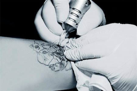 simsearch:400-03921001,k - A tattoo artist applying his craft onto the hand of a female Stockbilder - Microstock & Abonnement, Bildnummer: 400-05230945