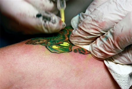 A tattoo artist applying his craft onto the hand of a female Fotografie stock - Microstock e Abbonamento, Codice: 400-05231419