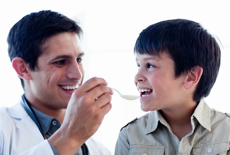 Self-assured doctor giving medicine to a little boy against a white background Stockbilder - Microstock & Abonnement, Bildnummer: 400-05232824