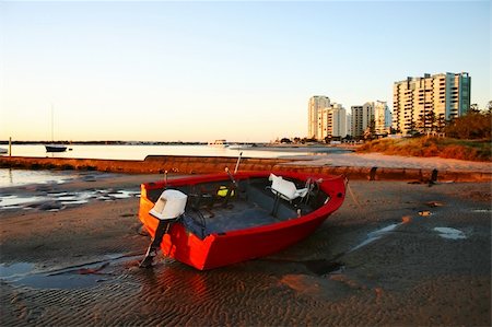 simsearch:400-05255037,k - Battered old red dinghy with outboard motor lies on the beach at dawn. Stockbilder - Microstock & Abonnement, Bildnummer: 400-05247087