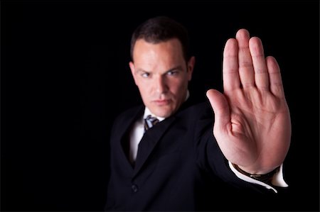 simsearch:400-06635276,k - Businessman with his hand raised in signal to stop, isolated on black background, Studio shot Photographie de stock - Aubaine LD & Abonnement, Code: 400-05247521