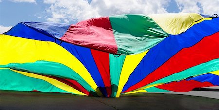 lone shadowy silhouette toddler crawling inside  technicolor parachute  breezy summer day carefree .contrast of tiny and gigantic Fotografie stock - Microstock e Abbonamento, Codice: 400-05248649