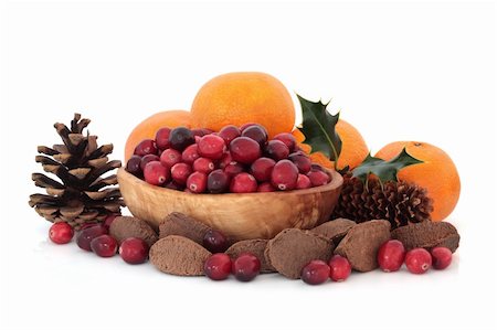 Cranberry fruit in an olive wood bowl with oranges, brazil nuts, holly leaves and pine cones,  isolated over white background. Stock Photo - Budget Royalty-Free & Subscription, Code: 400-05240195