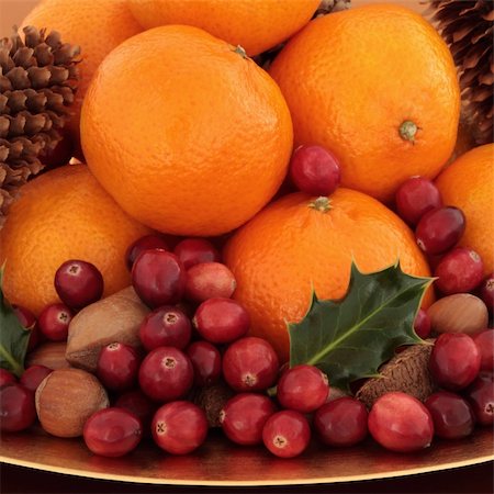 Cranberry and tangerine fruit with pecan, hazelnut and brazil nuts with pine cones and holly leaf sprigs. Stock Photo - Budget Royalty-Free & Subscription, Code: 400-05240276