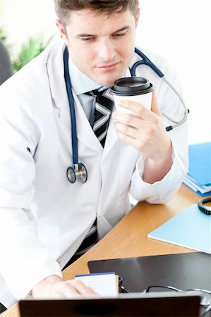 doctors coffee - Charming male doctor using a laptop and drinking coffee in the office Stock Photo - Budget Royalty-Free & Subscription, Code: 400-05240748