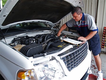 Auto mechanic performing a routine service inspection in a service garage. Foto de stock - Super Valor sin royalties y Suscripción, Código: 400-05241378