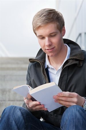 Young cheerful handsome guy reading a book with blank cover Photographie de stock - Aubaine LD & Abonnement, Code: 400-05254105
