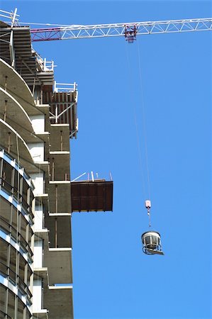 crane hoisting cement concrete mixer container up side of a work in progress highrise Fotografie stock - Microstock e Abbonamento, Codice: 400-05254654