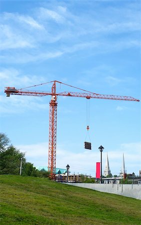 heavy machinery industrial crane  work in progress downtown with grassy hill slope in the foreground and sky in background Fotografie stock - Microstock e Abbonamento, Codice: 400-05254652