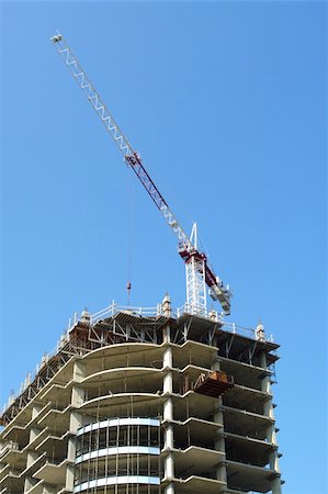 industrial derrick on roof top of multi story highrise in construction with blue sky background. Fotografie stock - Microstock e Abbonamento, Codice: 400-05254839