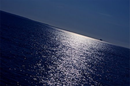 roxxer (artist) - Marine view of sun reflections in water and a large ship disappearing behind the horizon. Intentionally angled horizon line. Fotografie stock - Microstock e Abbonamento, Codice: 400-05256601