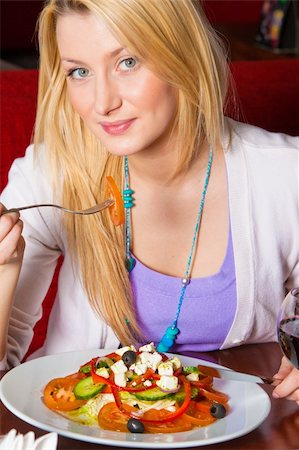 person eating greek salad - A young woman sitting in a restaurant. She is looking at the camera and smiling as she is eating salad. Vertical shot. Stock Photo - Budget Royalty-Free & Subscription, Code: 400-05258328