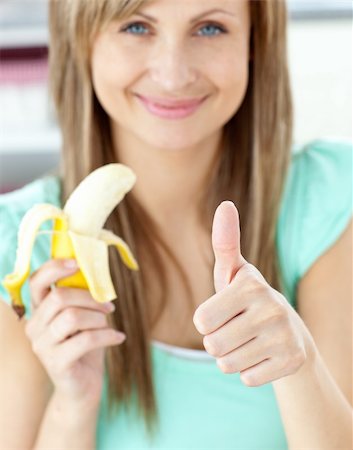 pretty women eating banana - Smiling woman with thumb up holding a banana in the kitchen at home Photographie de stock - Aubaine LD & Abonnement, Code: 400-05259730