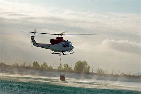 firefighters spray water - Fire brigade helicopter dipping the water container to refill Stock Photo - Budget Royalty-Free & Subscription, Code: 400-05253170