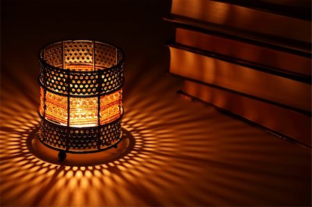 Old-style candlestick with flaming candle inside and some books in the dark Stock Photo - Budget Royalty-Free & Subscription, Code: 400-05253266