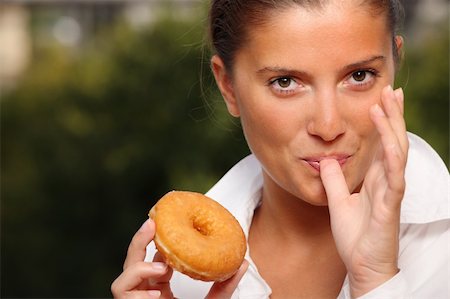 A picture of a woman trying to resist temptation of eating a donut over natural background Stock Photo - Budget Royalty-Free & Subscription, Code: 400-05268448