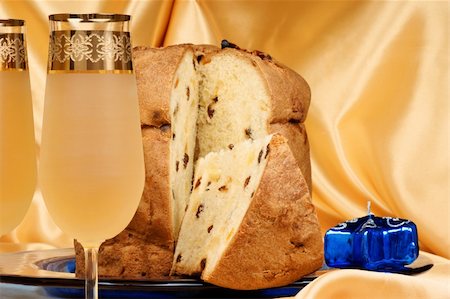 Panettone the italian Christmas fruit cake served on a blue glass plate over a yellow background and two glasses of spumante (sparkling wine). Selective focus. Foto de stock - Super Valor sin royalties y Suscripción, Código: 400-05268682
