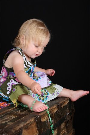 Beautiful blond toddler sitting on an antique trunk playing with beads Stock Photo - Budget Royalty-Free & Subscription, Code: 400-05276036