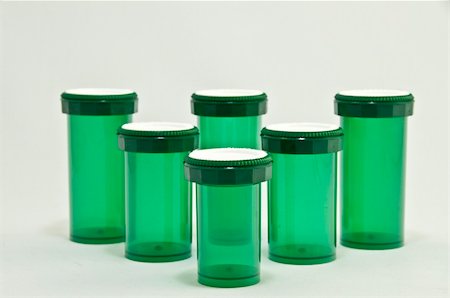 Five green medicine bottles with white caps. This is on a white background.Focus is on the front center bottle. Stock Photo - Budget Royalty-Free & Subscription, Code: 400-05273441