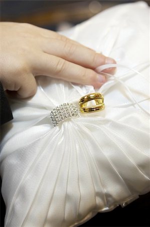 Wedding rings and wedding bands tied onto the ring bearers pillow.  The wedding bands are gold and the wedding ring contains many diamonds.  Focus is on the rings. Photographie de stock - Aubaine LD & Abonnement, Code: 400-05284670