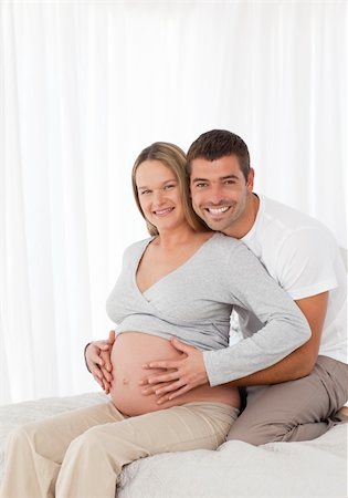 simsearch:400-04266844,k - Cute pregnant woman touching her belly with her husband in the bedroom at home Stock Photo - Budget Royalty-Free & Subscription, Code: 400-05286040