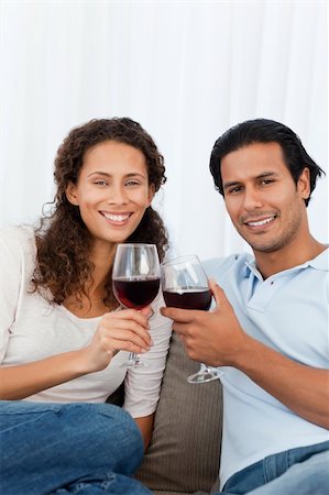 simsearch:400-04663577,k - Happy couple clinking glasses of red wine on the sofa in the living-room Stock Photo - Budget Royalty-Free & Subscription, Code: 400-05287144