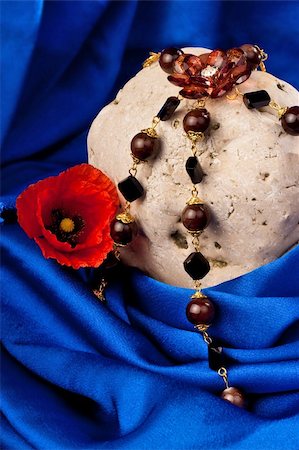 simsearch:630-01492287,k - Necklace, flower and stone on a blue textile. Vertical Foto de stock - Royalty-Free Super Valor e Assinatura, Número: 400-05295572