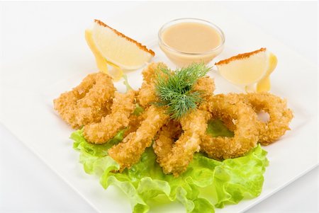 fried squid with salad leaves, sauce, green and lemon on a white background Stock Photo - Budget Royalty-Free & Subscription, Code: 400-05297382