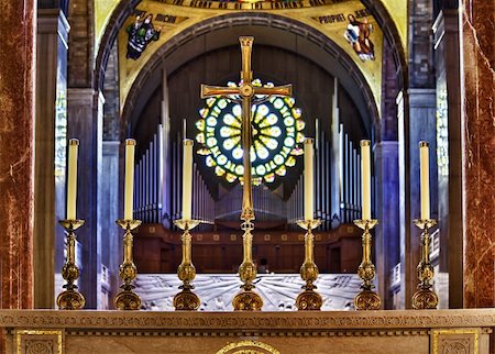 Set of ornate carved candlesticks on altar illuminated by sunlight with the brilliant window and organ pipes in the far background of the church Foto de stock - Super Valor sin royalties y Suscripción, Código: 400-05299772