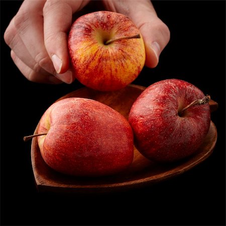 hand taking an apple from a wooden plate isolated on black background Stock Photo - Budget Royalty-Free & Subscription, Code: 400-05292145