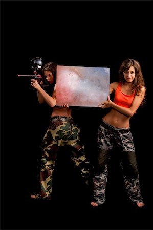 paintball - Two girls posing for camera and one holds a table like she advertise something Fotografie stock - Microstock e Abbonamento, Codice: 400-05293417