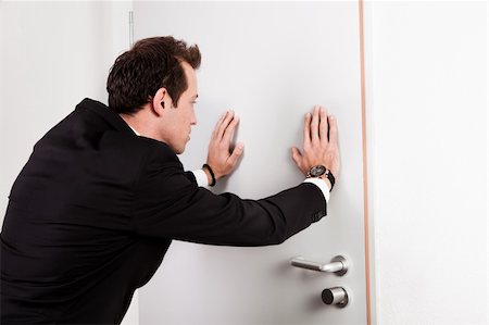 pushing door - Businessman pushing the door to prevent people entering room Stock Photo - Budget Royalty-Free & Subscription, Code: 400-05306302