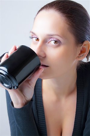 Beautiful young woman with eyes focused directly drink from black ceramic mug. Close-up isolated on neutral background. Stock Photo - Budget Royalty-Free & Subscription, Code: 400-05309264
