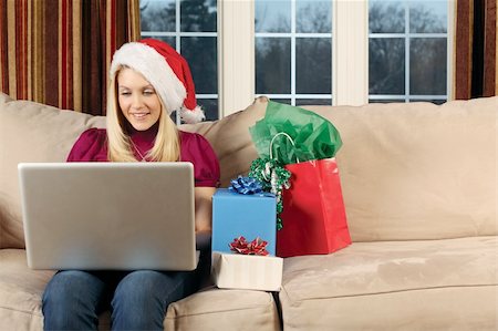 Photo of a beautiful blond female sitting on a couch using a laptop to shop for Christmas gifts. Stock Photo - Budget Royalty-Free & Subscription, Code: 400-05301910