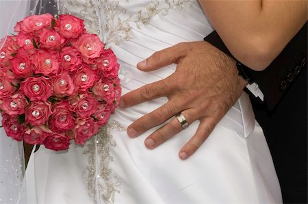 groom standing with his hand wearing a wedding ring and red bouquet on his brides bum Stockbilder - Microstock & Abonnement, Bildnummer: 400-05302900