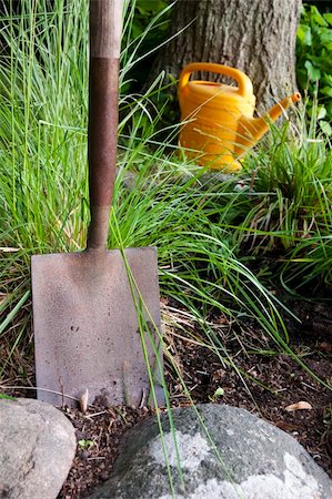 shovel in dirt - Close up of garden shovel with watering can in the background Stock Photo - Budget Royalty-Free & Subscription, Code: 400-05303494